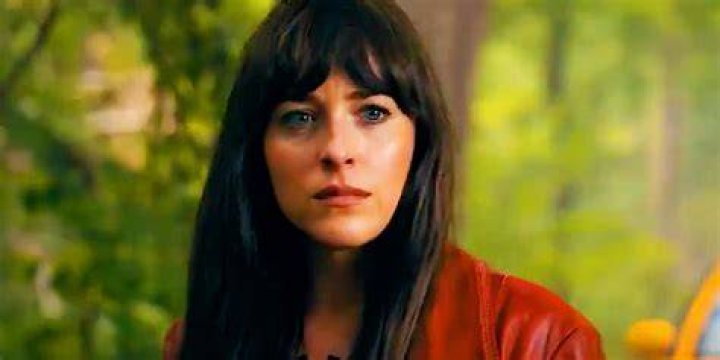 Dakota Johnson as Cassandra Webb in Madame Web Dakota Johnson as Cassandra Webb wearing a paramedics outfit and looking shocked, with her hair blowing across her face.