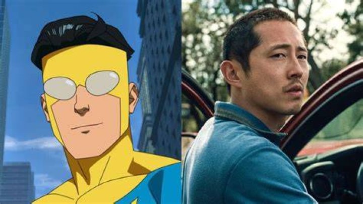 Steven Yeun (Mark Grayson) in Invincible season 2 in his yellow blue and black super suit, holding his mask
